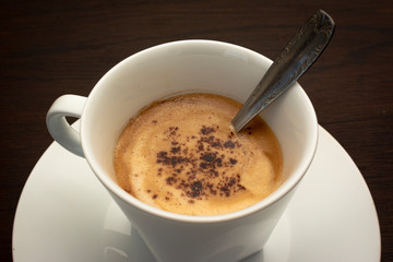 top view of white cup of coffee on a dark wooden table.