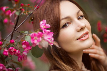 Obraz na płótnie Canvas portrait of a beautiful young woman with make-up near a tree with flowers