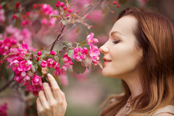 Fototapeta premium portrait of a beautiful young woman with make-up near a tree with flowers