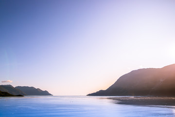 Cruise to Inside Passage of Alaska, beautiful sunset view on the mountains from the ship, a clear blue sky. Drifting ice in the sea, snowy cliffs and hills. © Denys Pechenenko