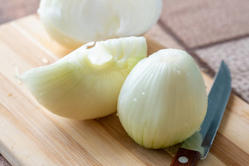 Peeled onions on a wooden board with a knife, food