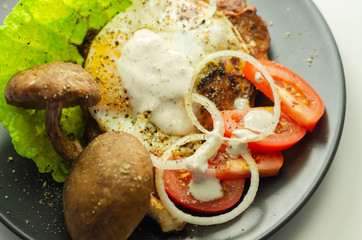 The fried portion of gammon served with egg, fresh lettuce, tomato, onion and funguses