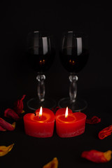 
a pair of glasses with wine and two burning candles in the form of a heart