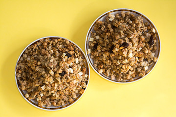 muesli fried cereals in a plate gold dried fruits raisins on a yellow background place for text