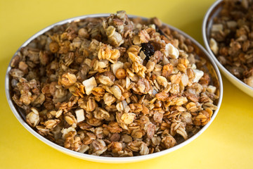 muesli fried cereals in a plate gold dried fruits raisins on a yellow background place for text