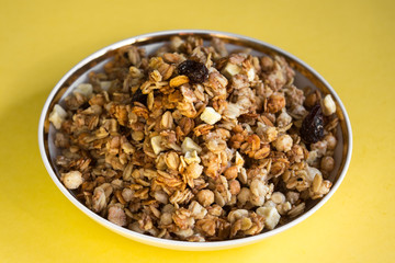 muesli fried cereals in a plate gold dried fruits raisins on a yellow background place for text