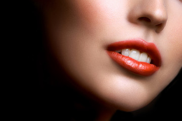Close-up portrait of beautiful young woman lips with bright red lipstick