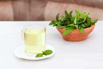 Obraz na płótnie Canvas Fresh herbal mint tea on white wooden table. Calm and health concept,