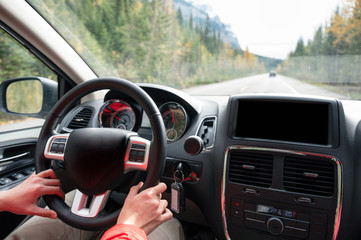 Man driving a car on the highway in autumn forest