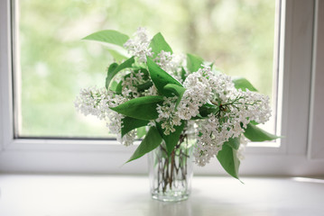 a bouquet of white flowers in a transparent vase on the window