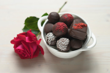 Chocolate candies assorted on a white background with red rose