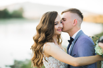 Obraz premium Wedding couple, groom and bride hugging, outdoor near river