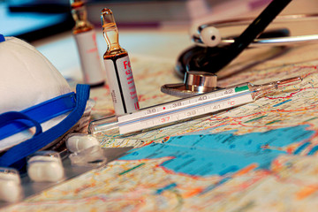 Face mask on a world map with pills and vaccine for covid 19