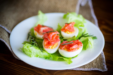 boiled eggs with salted red fish and salad leaves
