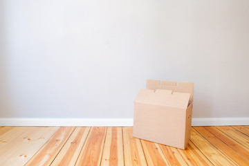 cardboard box in empty room, moving in new flat
