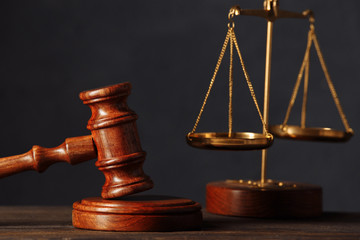 Law and justice concept. Lawyers desk. Judge's gavel close-up, scales, wooden table. Dark gray bokeh background.