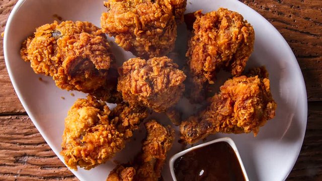 Rotation Bucket full of crispy kentucky fried chicken with smoke on brown background.