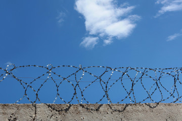Barbed wire over a concrete wall. The concept of incarceration. Photos without people. Copy of the space.