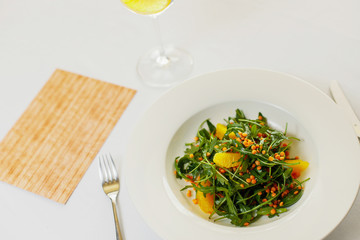 salad of arugula, orange fillet and lentils on a white plate