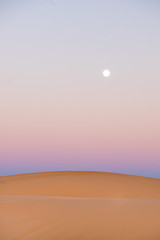 desert light at dusk with orange color and purple with full moon