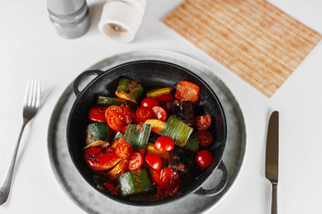 vegetable pan on a white table next to the menu, salt and pepper