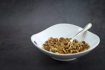Pancake cereal. Trendy food, mini cereal pancakes in bowl on the table, grey cement background. Trendy baked mini pancakes with strawberries, blueberries . Copy space. Flat layout. Table top view.