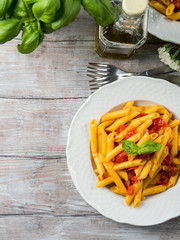 Penne pasta with fresh tomatoes and basil on wooden table. Traditional italian dish
