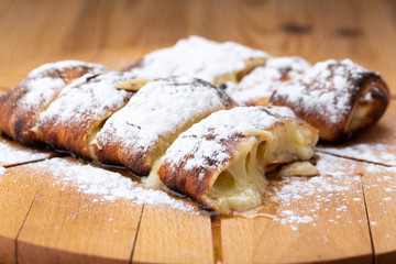fruit strudel on a wooden board sprinkled with icing sugar. delicious pastries
