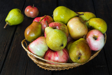 Apples and pears in a basket and honey on a black background.