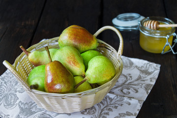 Apples and pears in a basket and honey on a black background.