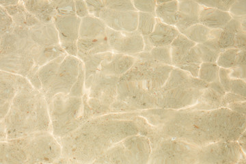 Natural texture and background. Sunlight and glare on the water. Yellow sandy bottom of the sea