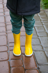 Boy in yellow boots in the rain