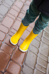Boy in yellow boots in the rain