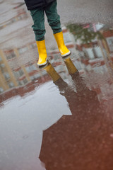 Boy in yellow boots in the rain