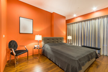 Naklejka na ściany i meble Bright orange bedroom with king-size grey bed with bedside tables and lamps