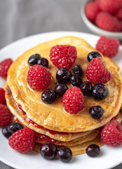 Sweet homemade pancakes with fruits on white plate.