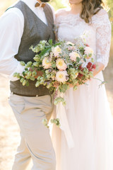 filled with light, a gentle cropped frame where the bride and groom hug each other holds a sloppy bouquet flowers.
