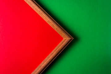 Fototapeta premium Wooden frame on a green background. Inside the frame is a red background. The frame occupies half the space. empty space for an inscription.
