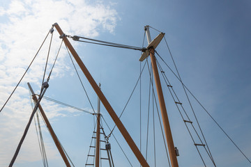 Masts with rigging, block and tackle, old sailing vessels silhouetted against a blue sky, horizontal aspect