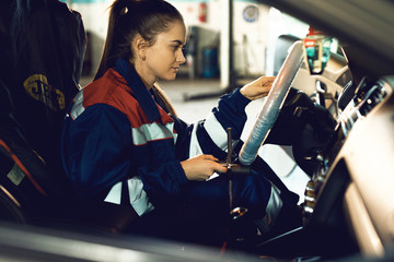 A female mechanic behind the wheel of a car