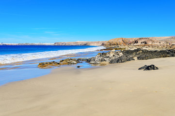 View of beautiful Playa de la Cera beach, blue sea, yellow sand, cliffs. Papagayo, Playa Blanca, Lanzarote, Canary Islands, selective focus