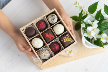 In the hands of a box of chocolates holds. assorted chocolates confectionery in their gift box on the white background
