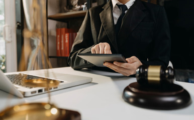 Justice and law concept.Male judge in a courtroom with the gavel, working with, computer and docking keyboard, eyeglasses, on table in morning light