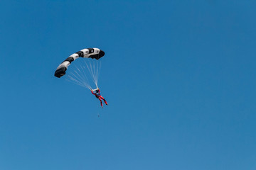 human silhouette running a colorful parachute in the blue sky
