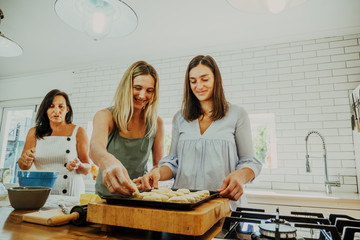 Sisters baking scones together while mother looks on