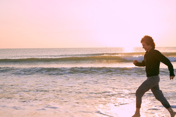 Athletic young caucasian girl jogging on the beach one sunny morning. 