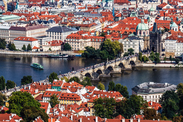 Panoramic view from above of Prague, Charles bridge with crowds of tourists, the Vltava river and red roofs. Czech Republic