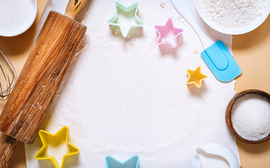 Rolling pin, baking ingredients and star shaped cookie cutters on a light background, top view, free space for text. Baking background, cooking cookies, homemade food.