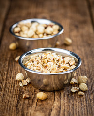 Freshly chopped Hazelnuts on an old wooden table (close up; selective focus)