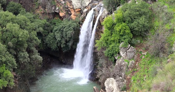 High waterfall and greenery all around.